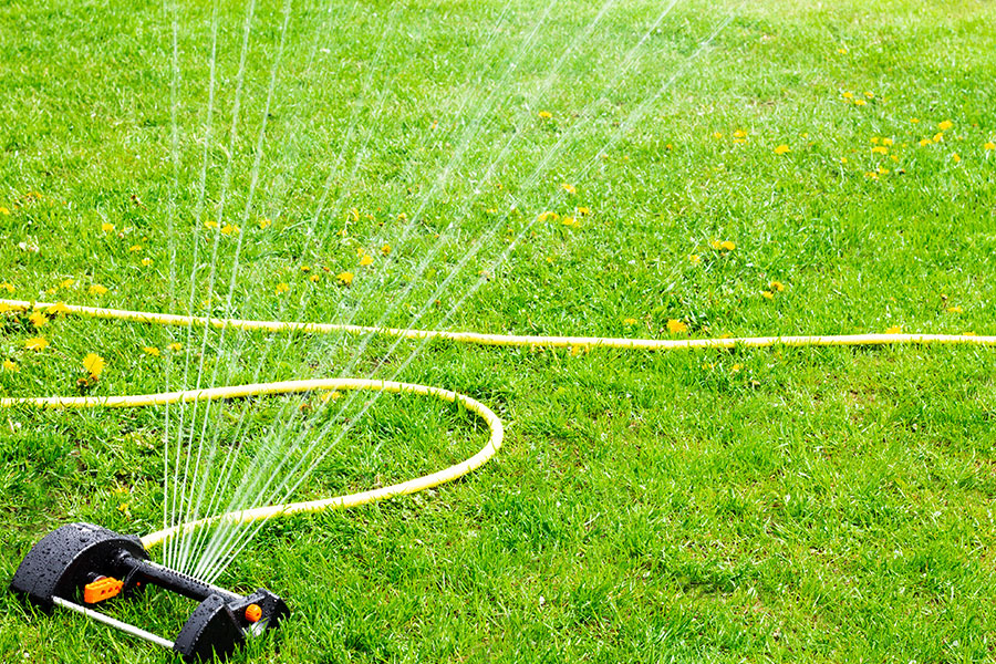 A spring lawn being watered by a sprinkler in Troy, IL to keep grass, trees, and bushes healthy in the new year.