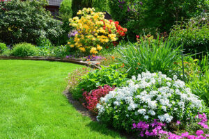 A residential yard in Edwardsville, IL with thriving flowers, bushes, and trees to bring diversity to the property in the summer.